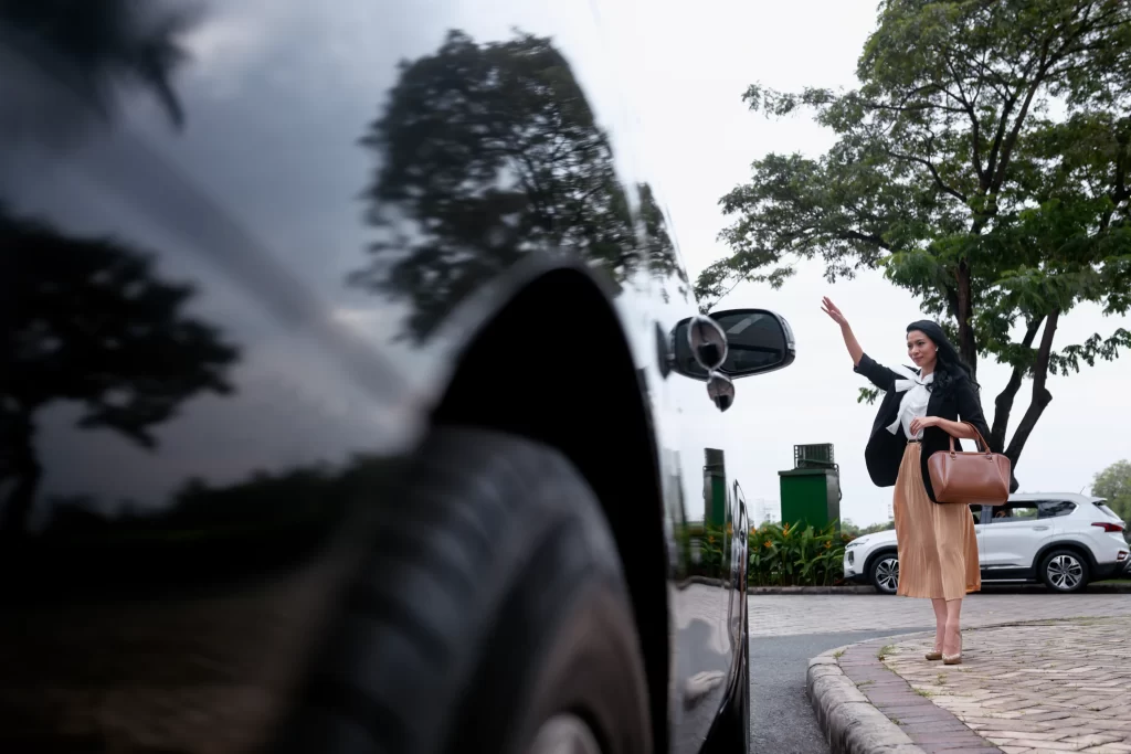 Business woman waving for private transfer service outside airport