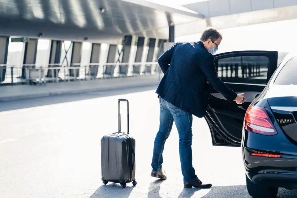 Man opening car door after returning from abroad, arriving for private transfer