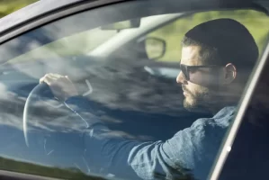 Male chauffeur wearing sunglasses driving a private transfer vehicle